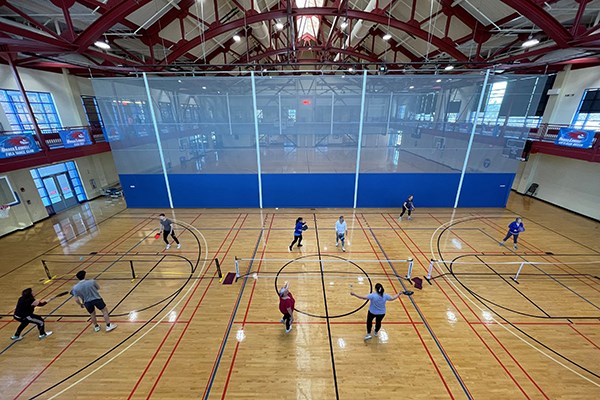 An overhead view of three pickleball courts set up in a gym