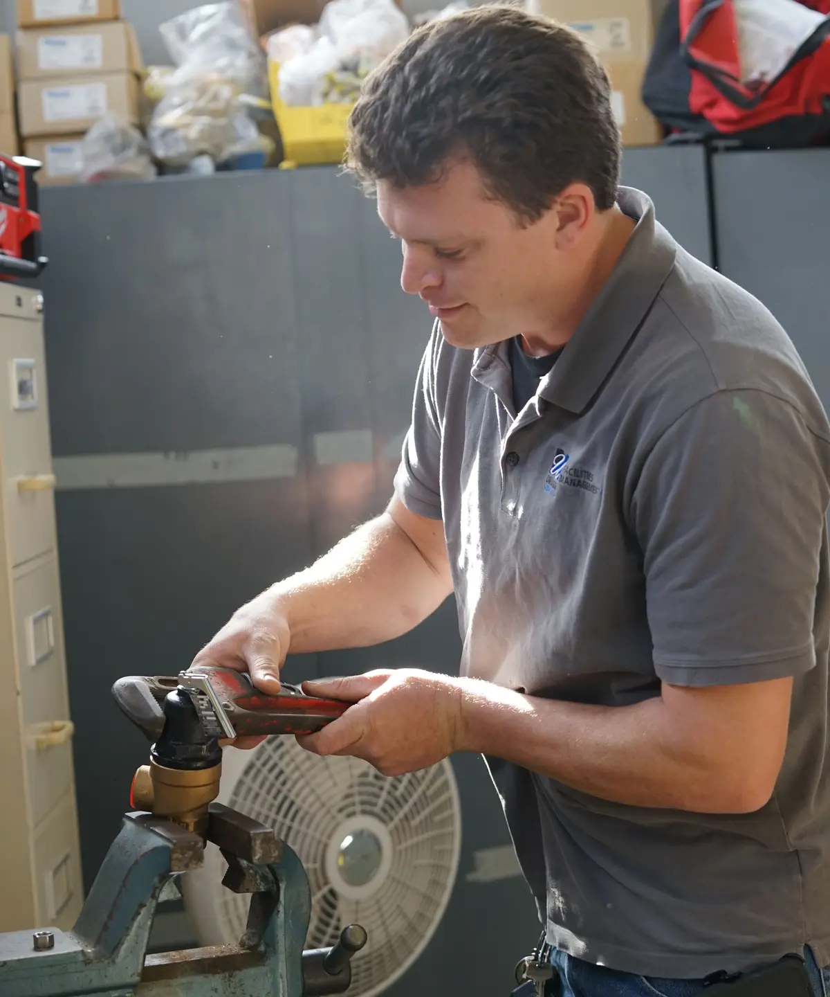 Man using pipe wrench on pipe in workshop