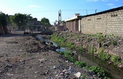  Poor sanitation in the area of Dlo Gervier, Cap-Haitien, Haiti : solid waste on the ground, drainage channel blocked, plastic bags containing excreta, road damaged by runoff water.