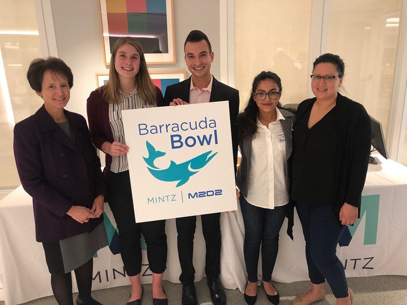  Pratibha Gautam with a group of people holding a "Barracuda Bowl" M2D2 poster.