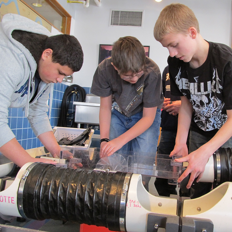 Three older boys building a water flow system at Tsongas Industrail History Center