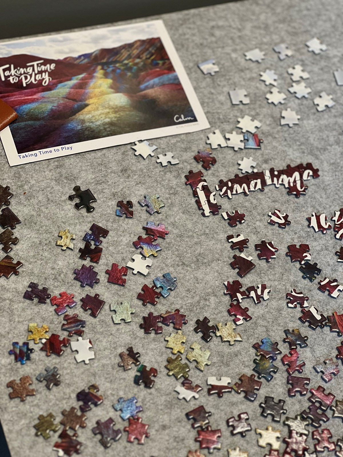 multicolored puzzle on puzzle mat with the writing "taking time to play"