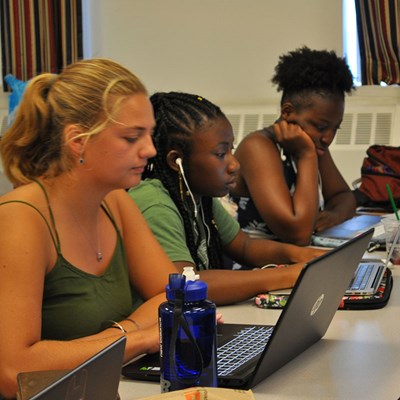 Three young women work on laptops at a table