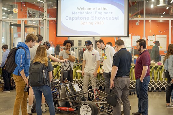 A group of students admire a race car that fellow students built during an engineering showcase