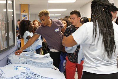 Members of the River Hawk Scholars Academy at UMass Lowell grab t-shirts.