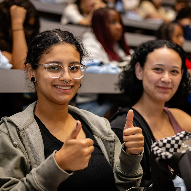 During welcome day for first-generation students a woman gives booth thumbs up.