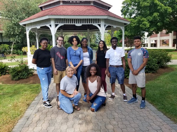 A group of River Hawk Scholars Academy Peer & Team leaders pose outside in front of the gazebo on South Campus