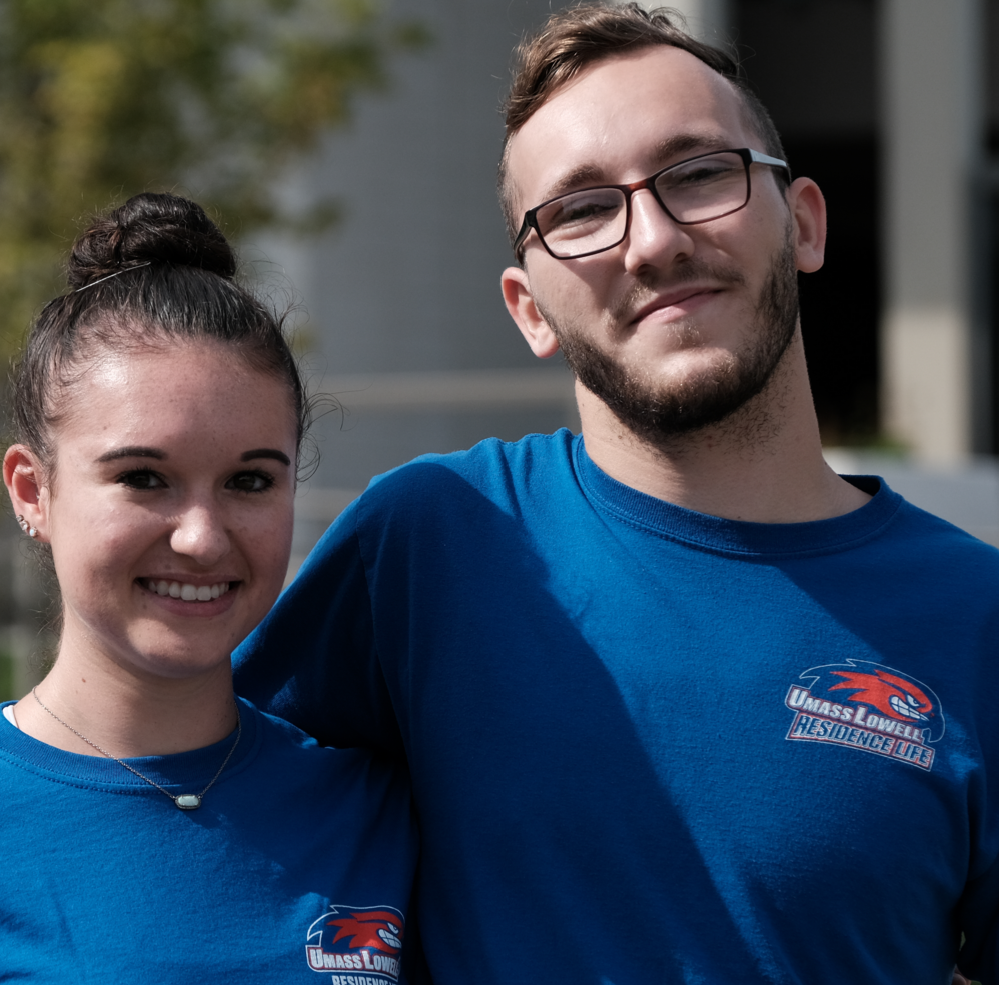 2 students standing together, both wearing blue shirts with "Residence Life" printed on chest.