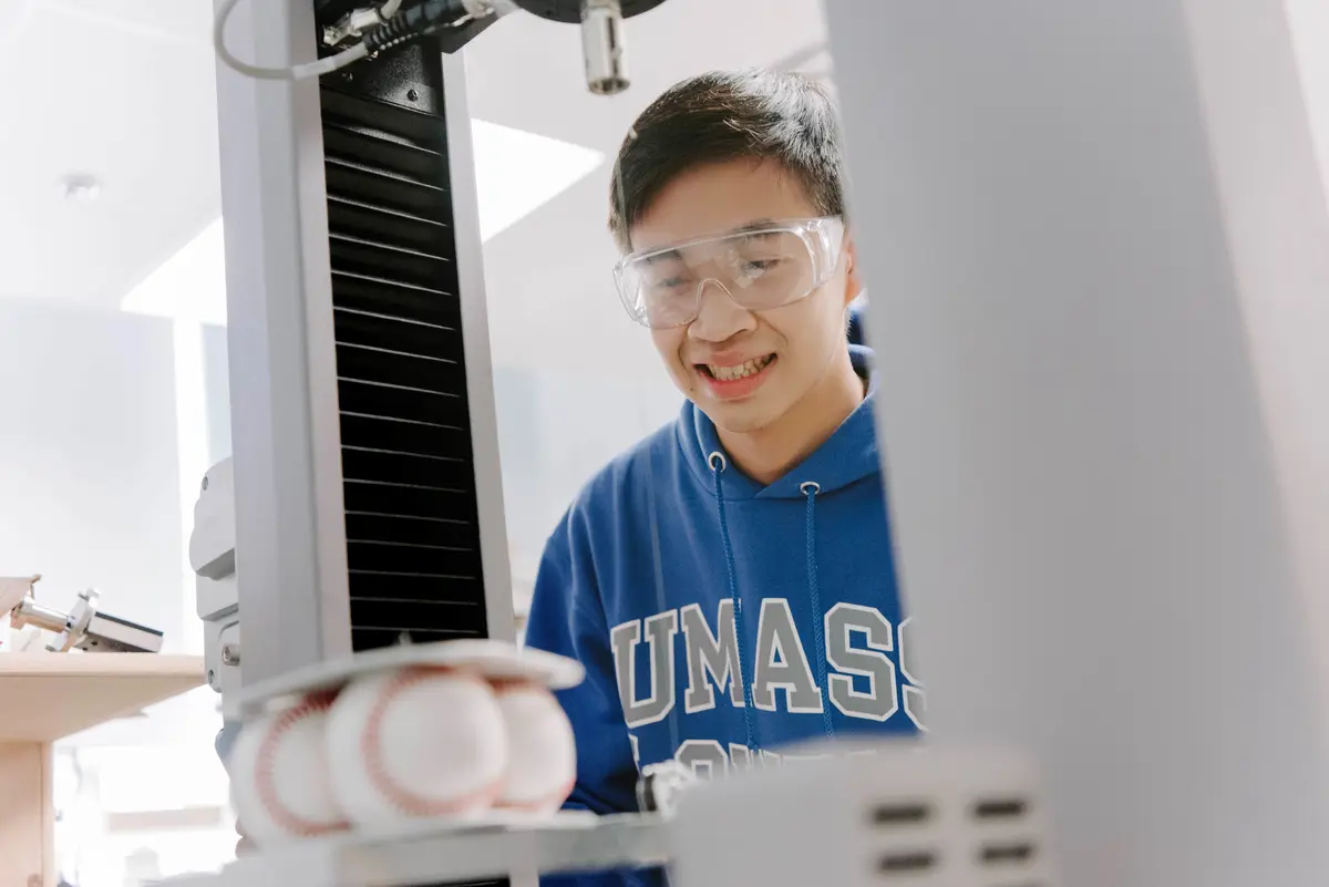 A student uses a machine to test the performance of baseballs.