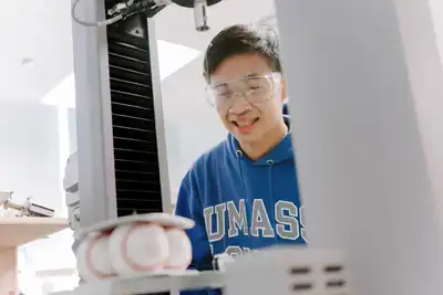 A student uses a machine to test the performance of baseballs.