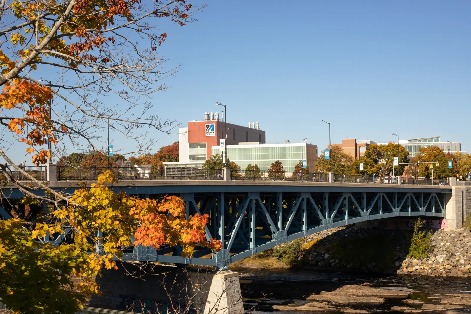 The Howe Bridge and UMass Lowell's Saab Emerging Technologies and Innovation Center amidst fall foliage and colored leaves.