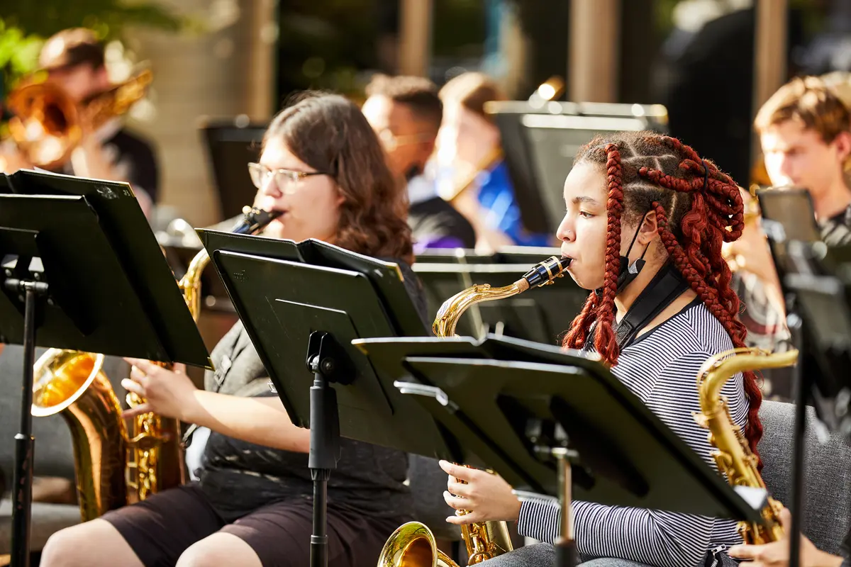 UMass Lowell students seated playing musical instruments.
