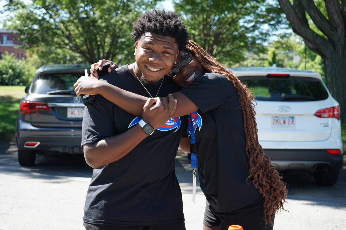 2 students hugging, both wearing black shirts with Rowdy Logos on the chest.
