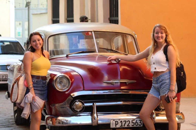 Rachel Jordan and friend pose with classic car in Cuba
