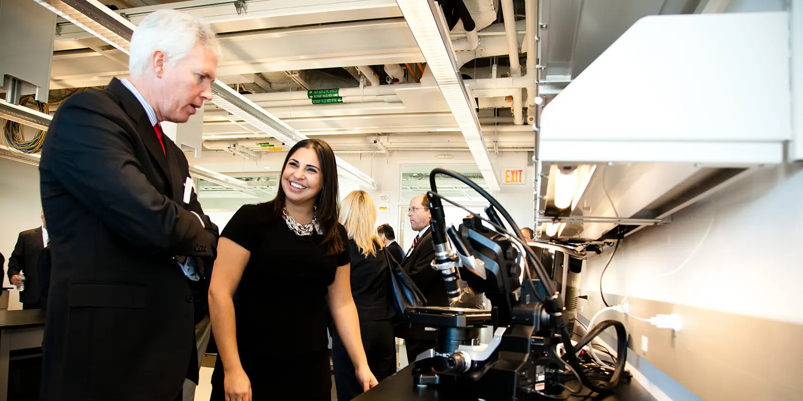 A staff member shows a guest a lab instrument at the Raytheon-UMass Lowell Research Institute.