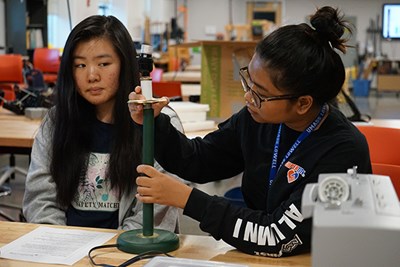 Amy Chan watches Angenie Pang pull a lamp apart at a training session for the SWE Repair Cafe at UMass Lowell