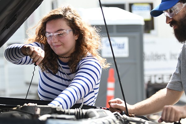 Alexandra Van Overbeeke-Costello, a member of the RiverHawk Racing club on campus, checks the oil in a truck at the UMass Lowell Repair Cafe.