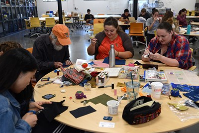Veronica Brown (center) helps out at the sewing table at UMass Lowell's Repair Cafe