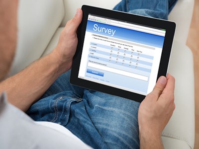 Person with tablet in lap and word Survey with survey choices on screen.