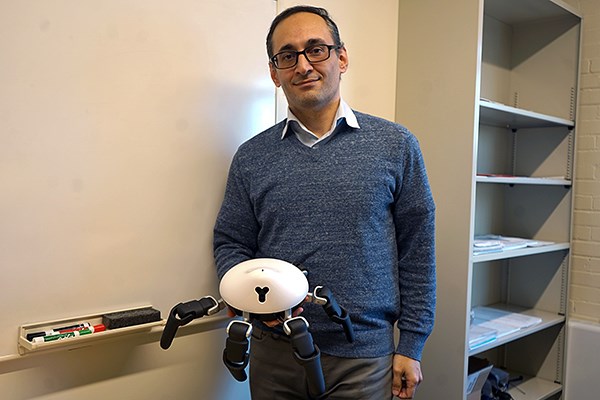 Asst. Prof. Reza Ahmadzadeh holds a HEXA robot.