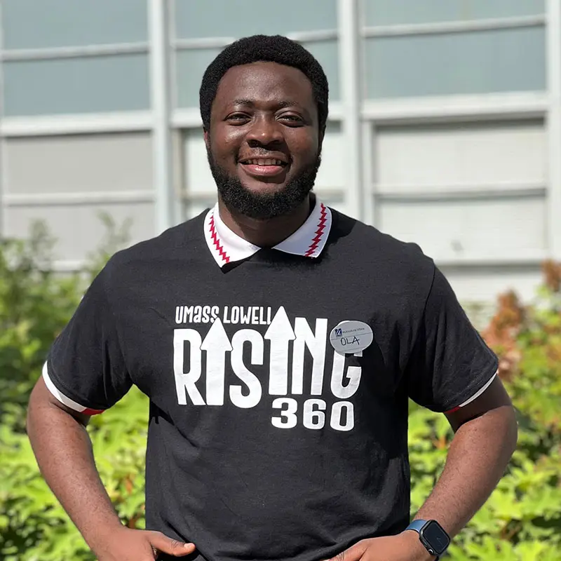 A student wears a black t-shirt that says "UMass Lowell Rising 30".