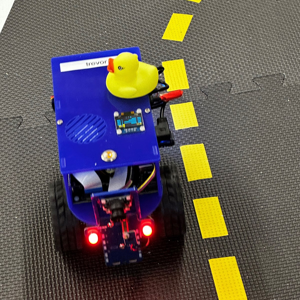 An electric robotic toy car with a rubber duck sitting on top.