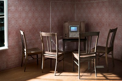 Photo of model of room with four empty chairs facing a 1950s Soviet TV set