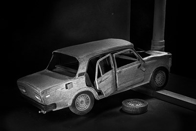 Photo of paper model of Soviet Lada-style car hitting a telephone pole, with one wheel off