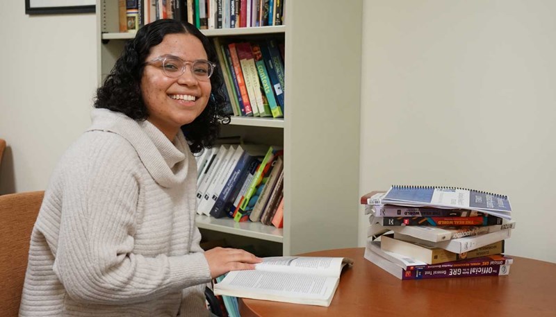 UMass Lowell student Rosmery Medrano sits at a table with an open book