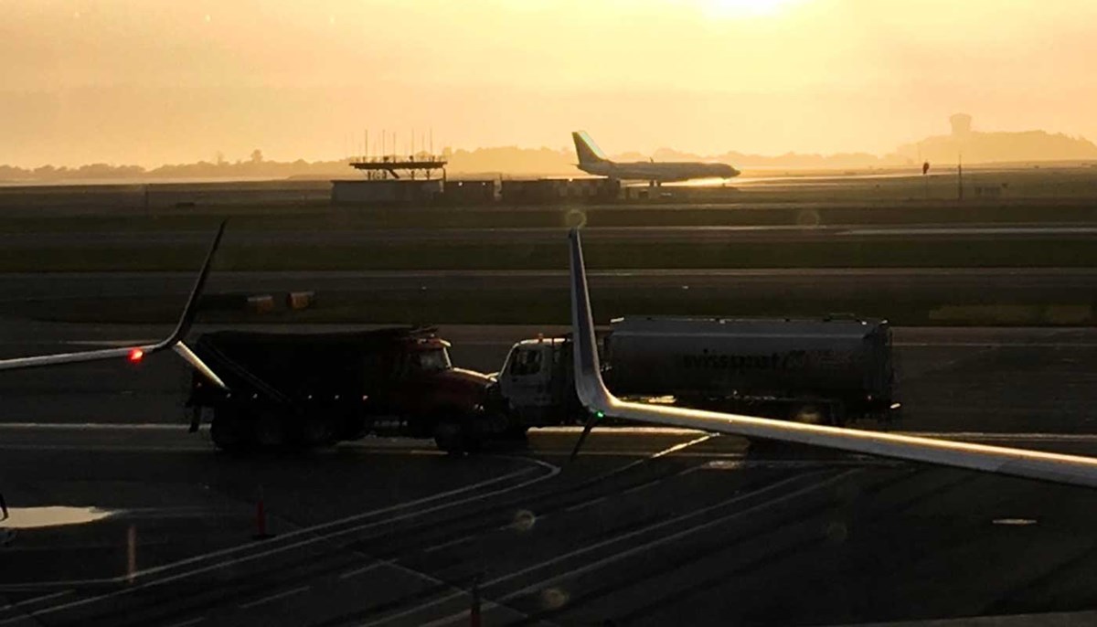 Plane and trucks on an airport runway.