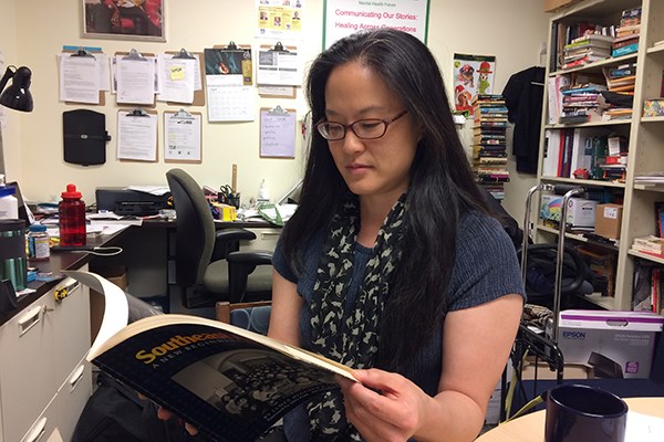 English Prof. Sue Kim looks through Higgins & Ross book of photos of Cambodian refugees in Lowell