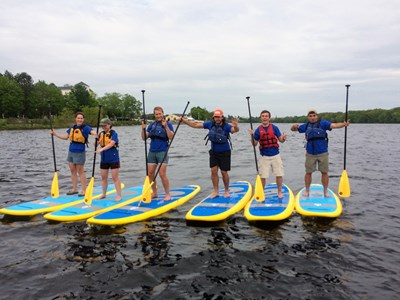 Six people on paddleboards with hands in the air
