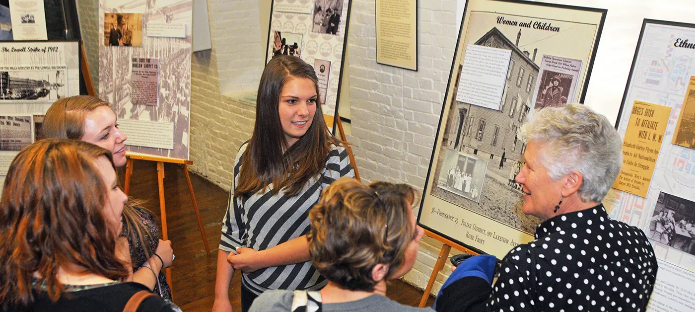 Faculty and students discuss a poster describing Lowell labor history