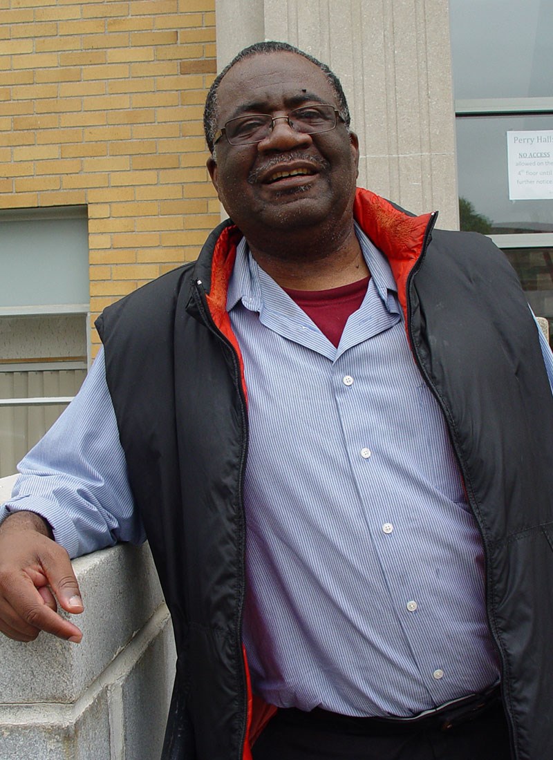 UMass Lowell alumni Sadrac Noel standing in front of a building on North Campus