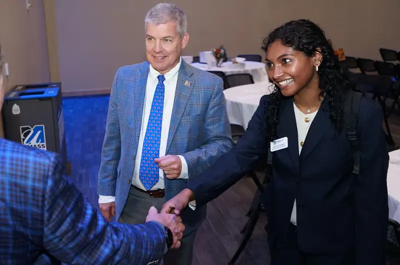 Sahana Sivarajan shaking hands with a person while standing with another person.