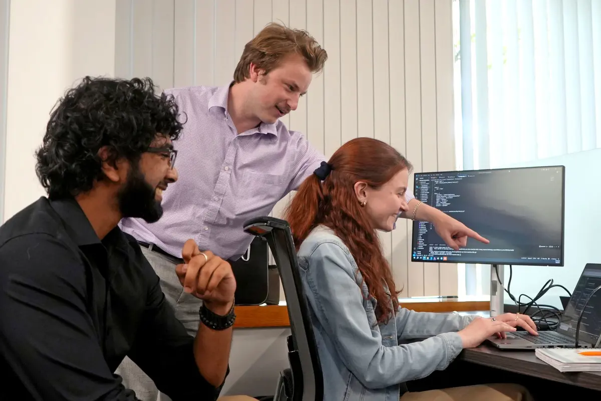 Said Siddiqui, John Ohrn and Amelia Halloran huddle around a laptop