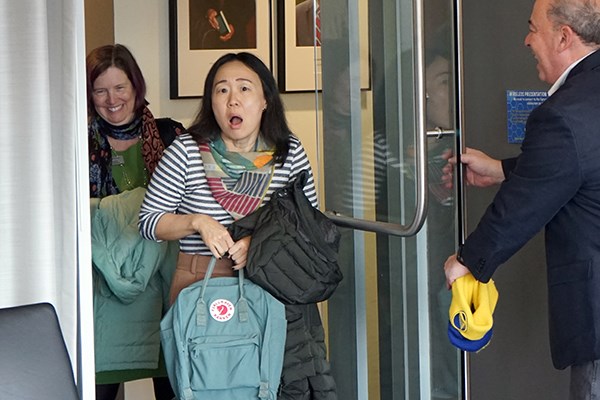 A woman looks surprised as she enters a room holding a backpack.