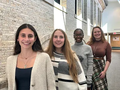 Sarah Merrill and three women members of her research team stand in order of height against a stone railing