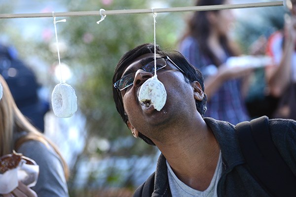 A student bobs for a donut at the block party