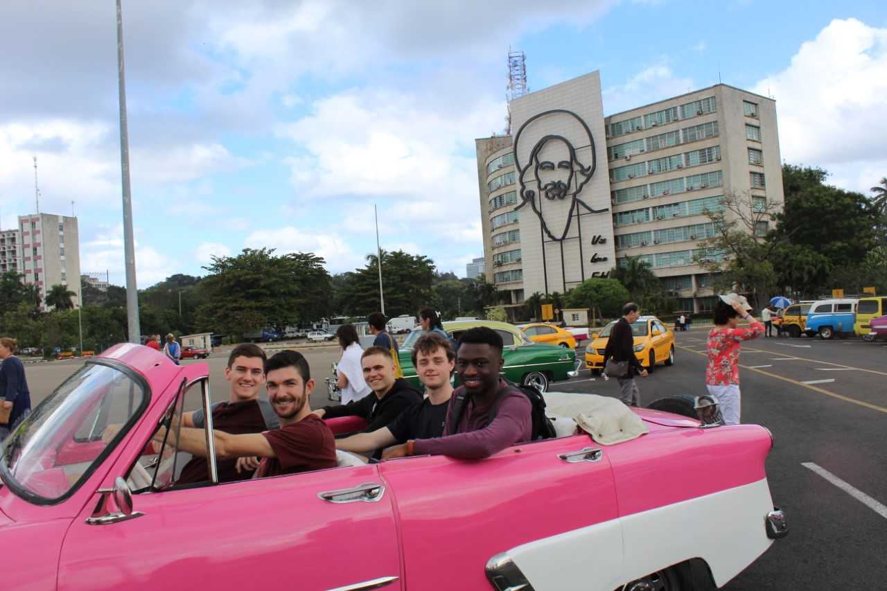 Scott Penfield drives a retro pink convertible filled with four passengers in Cuba.