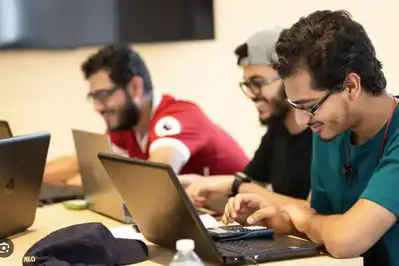 Three students type on laptops.