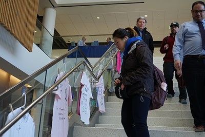 UML student Zhi Luo looks at T-shirts about sexual violence, part of the Clothesline Project displayed in University Crossing