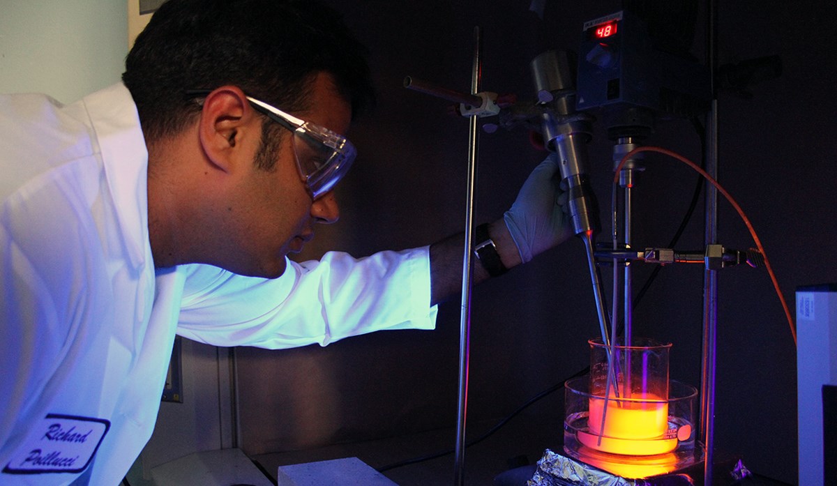 Mechanical engineering Ph.D. student, Siddharth Dev using unnamed equipment and a beaker that is glowing