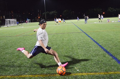 student playing soccer on campus rec complex turf field