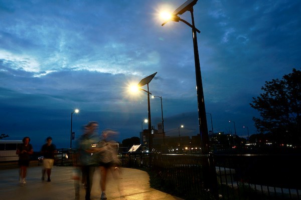 People are a blur walking under two solar street lights
