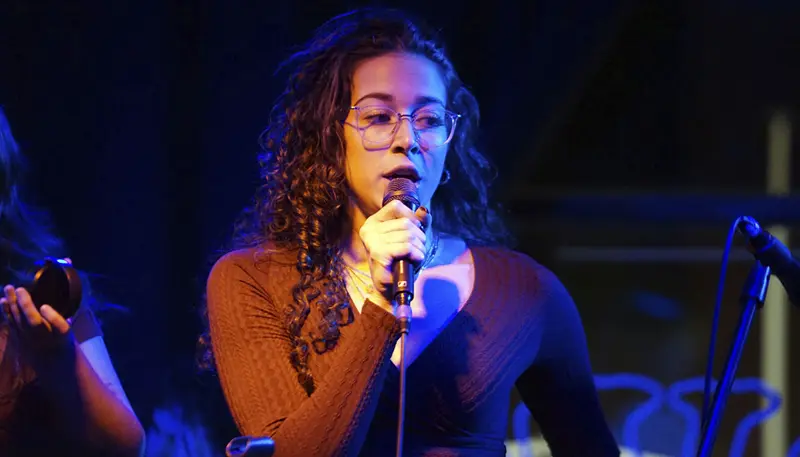 Umass Student Sophia Cavalcante sings into a microphone.