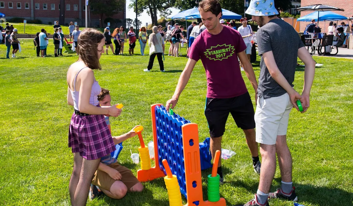 Four student play Connect 4 on a giant board outside