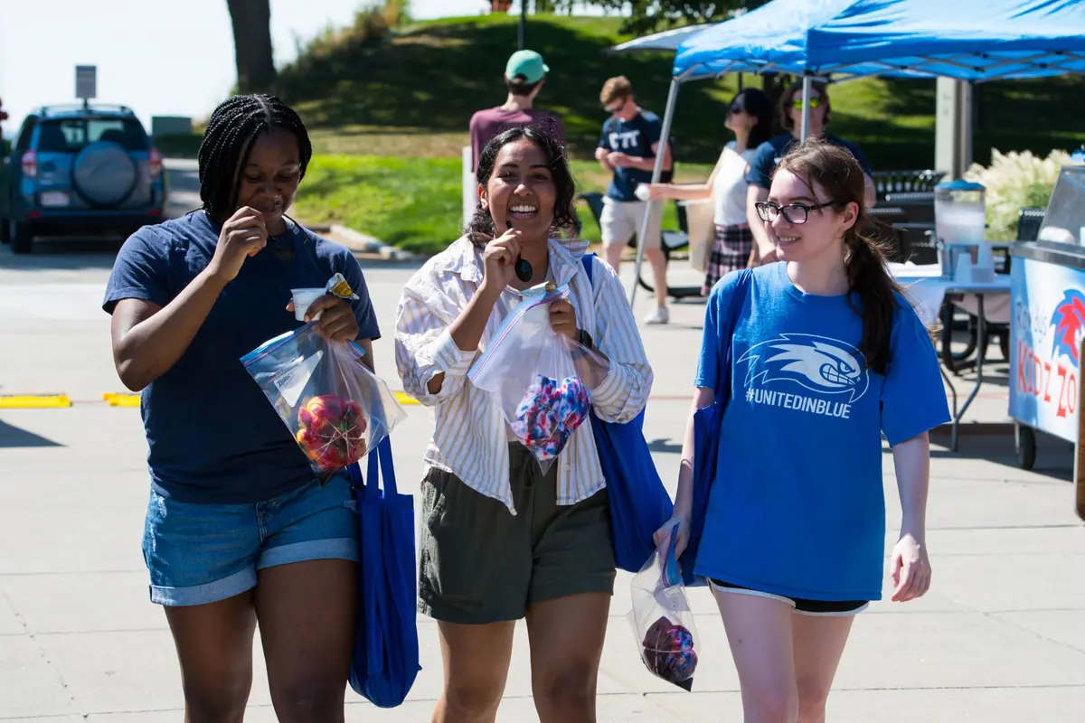 Three you women carry swag bags and eat ice cream