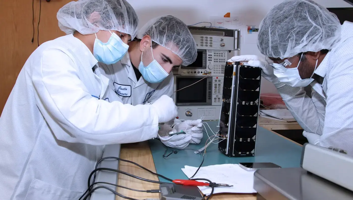 Three scientists in lab clothing work on a prject