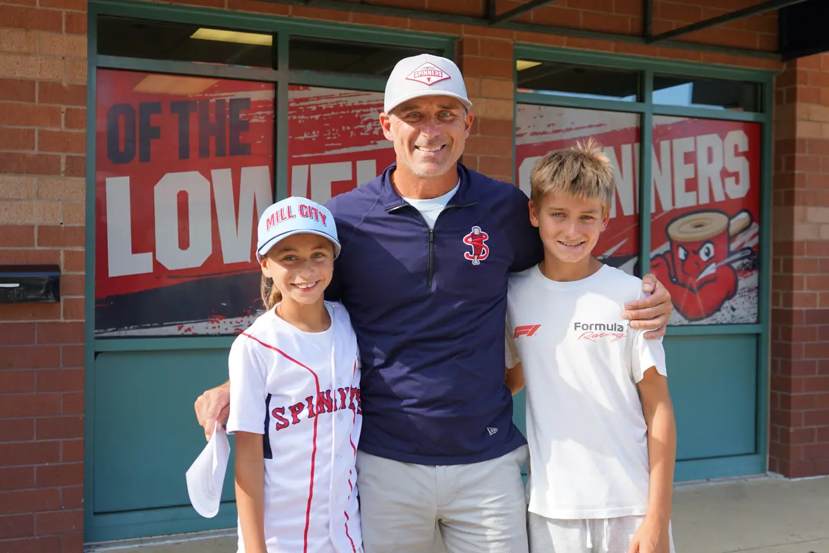 A man poses for a photo with his daughter and son outside of a baseball stadium.